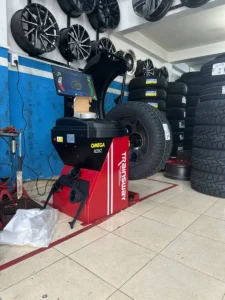 Máy cân bằng lốp OMEGA TRAINSWAY 828Z chính hãng đang hoạt động tại garage, màn hình hiển thị thông số kỹ thuật.