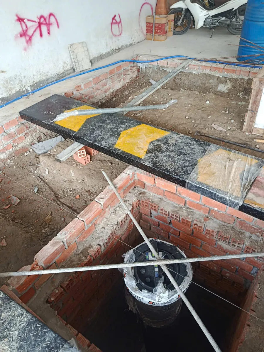 Cận cảnh quá trình lắp đặt cầu nâng 1 trụ âm nền Lộc Phát, cho thấy ty ben và khu vực hố móng.