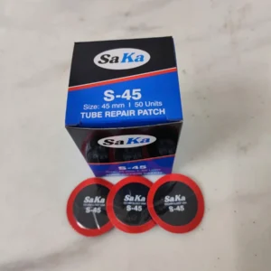 Hộp miếng vá săm lốp SAKA-TECH S45 và 3 miếng vá viền đỏ trên bàn thợ